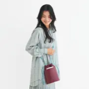 ボルドーの巾着バッグを持つ女性